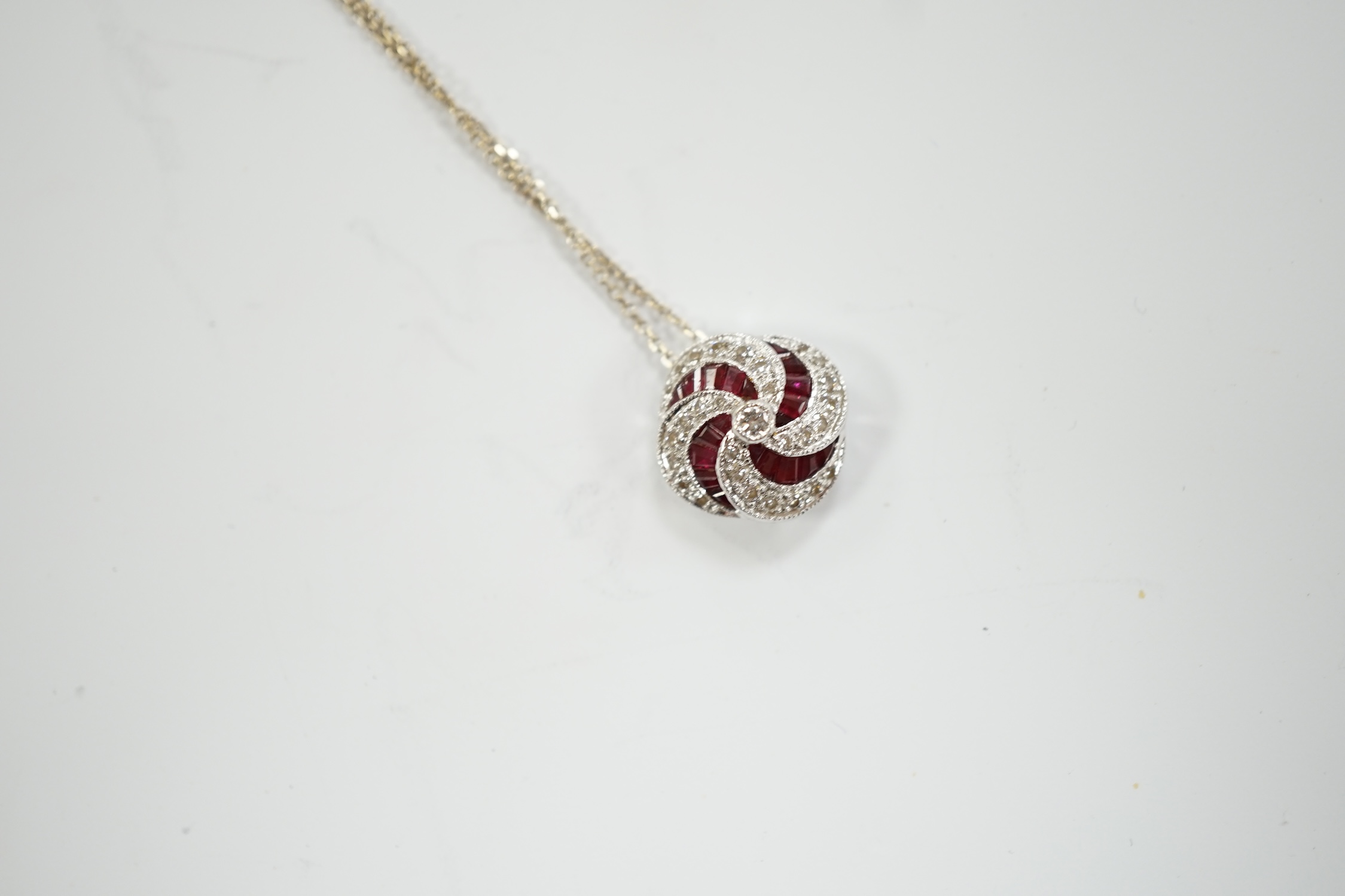A modern 18ct white gold, ruby and diamond cluster set pendant, 14mm, on a 750 white metal fine link chain, 39cm, gross weight 3.4 grams.